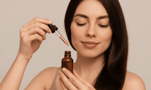 En esta imagen vemos a una mujer joven aplicando aceite capilar con un gotero cerca de su cabello largo y brillante. Su expresión es tranquila y cuidadosa, como si estuviera concentrada en su rutina de cuidado personal. Esta escena ilustra de forma perfecta la duda que muchas tenemos al usar aceites capilares: ¿El aceite hace que el cabello se engrase más? La imagen transmite una sensación de suavidad, hidratación y atención al detalle, ideal para acompañar artículos o blogs que aborden mitos y verdades sobre el uso de aceites en el pelo.









