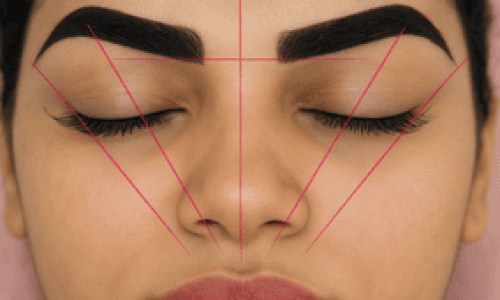 Primer plano del rostro de una mujer con los ojos cerrados, mostrando un diseño de cejas marcado con líneas guía en color rosa. Las líneas están trazadas de forma simétrica desde el centro de la nariz hacia los extremos del rostro, creando triángulos perfectos que ayudan a definir la forma ideal de las cejas. Este método visual representa claramente cómo hacer cejas simétricas, destacando los puntos clave de inicio, arco y final de cada ceja para lograr armonía facial.









